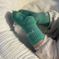 Green socks with text worn by a person on a light-colored surface